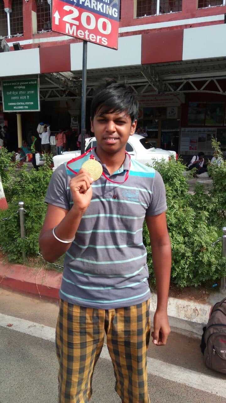 A boy holding up a gold medal.